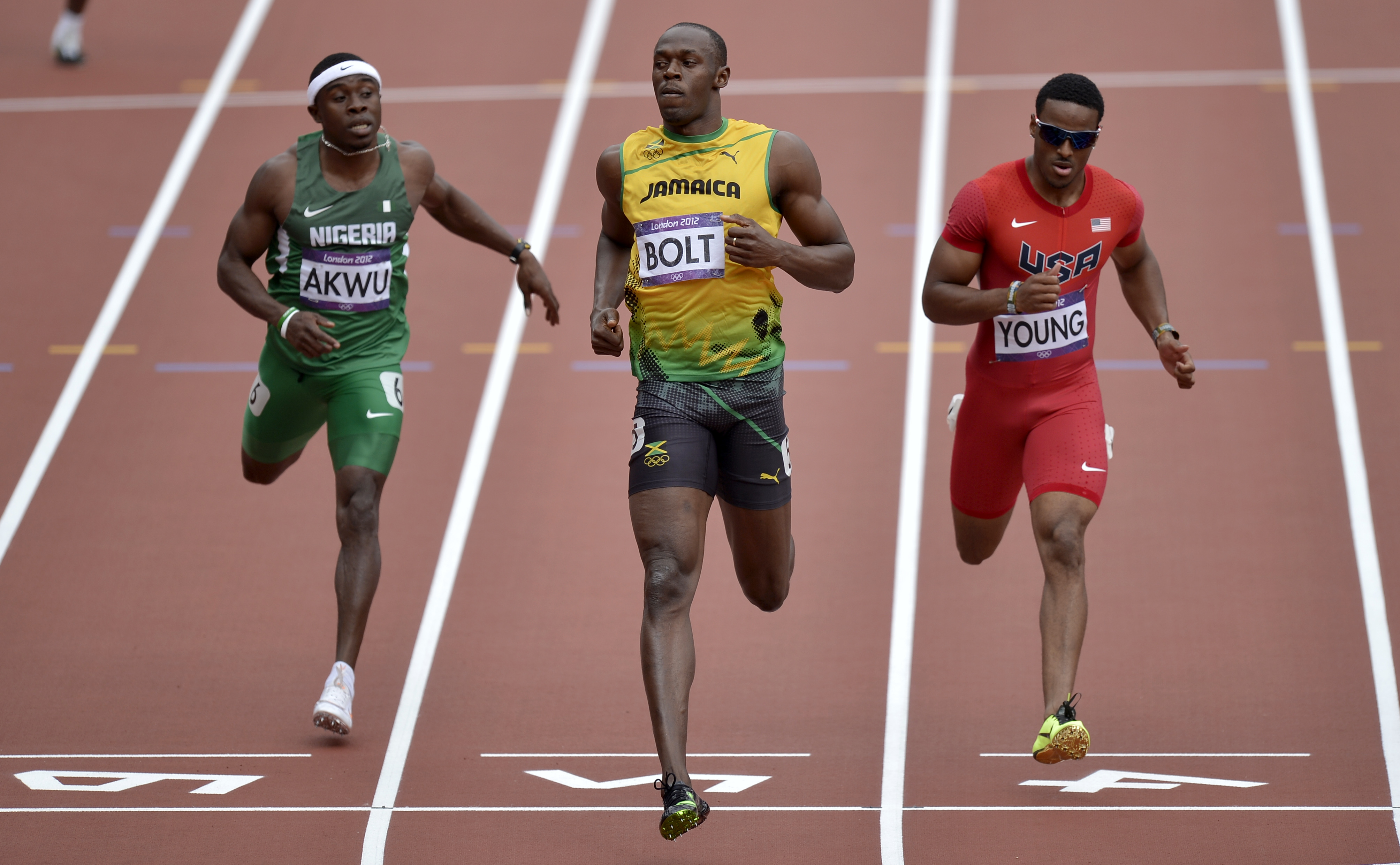 Nigeria's Noah Akwu, left, Jamaica's Usain Bolt, center, and United States' Isiah Young, right, cross the finish line in a men's 200-meter heat during the athletics in the Olympic Stadium at the 2012 Summer Olympics, London, Tuesday, Aug. 7, 2012.(AP Photo/Martin Meissner)
